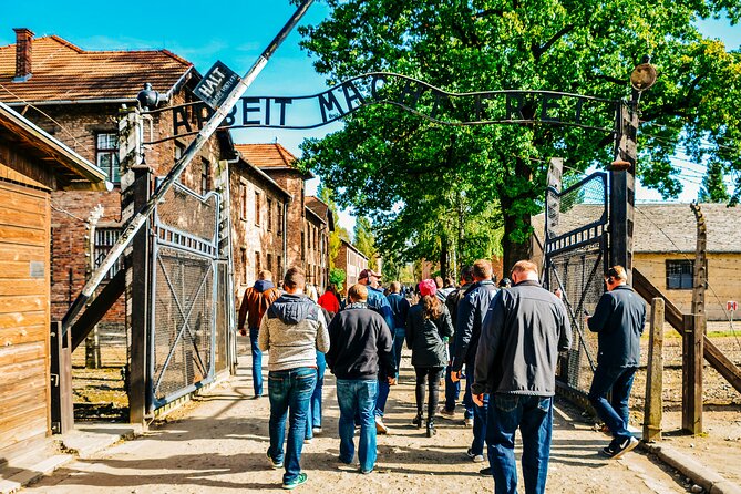 Day Tour to Auschwitz Birkenau Museum with Transportation - Entering Auschwitz I: Arbeit Macht Frei, headsets, and the main-camp impact